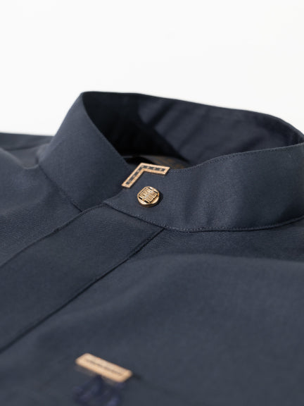 Close-up of a navy blue Saudi Thobe collar with gold buttons and trim on a light gray background